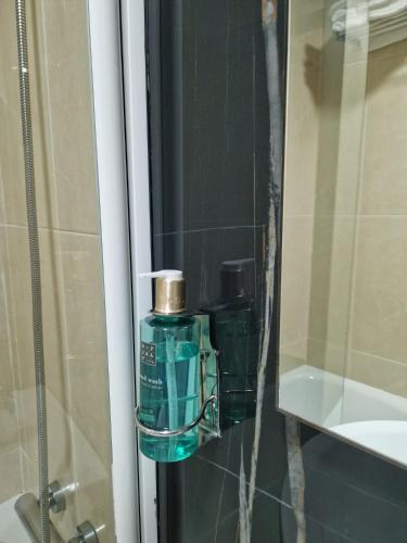 a green bottle of soap in a bathroom mirror at Hotel Los Girasoles by Maxi Hoteles in Granada