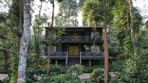 a house with a yellow door in the middle of trees at Machaan Wilderness Lodge Nagarahole in Srimangala