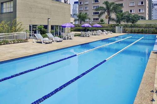 uma grande piscina com cadeiras e guarda-sóis em M-Flat III Luxo - Hotel em São Paulo