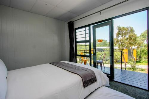a bedroom with a bed and a large window at SleepOver Kruger Gate in Skukuza