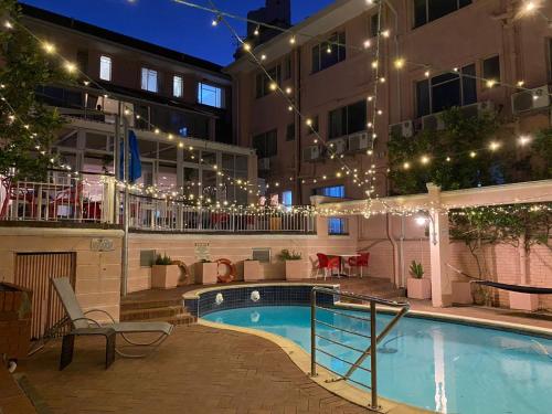 una piscina por la noche con luces y un edificio en Auberge Gardens, en Ciudad del Cabo