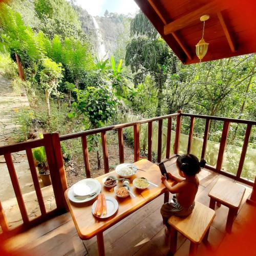 a little child sitting at a table on a porch at Diyaluma View Cotage in Koslanda