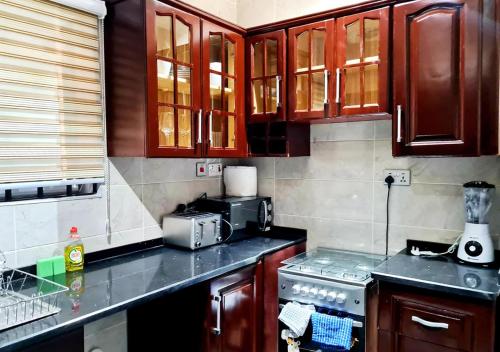 uma cozinha com armários de madeira e um fogão em Elegant Escape in Adenta- 2-Bed, 5star Service, Free Wifi, 24-7 Security, Close to Highway, by DLA 