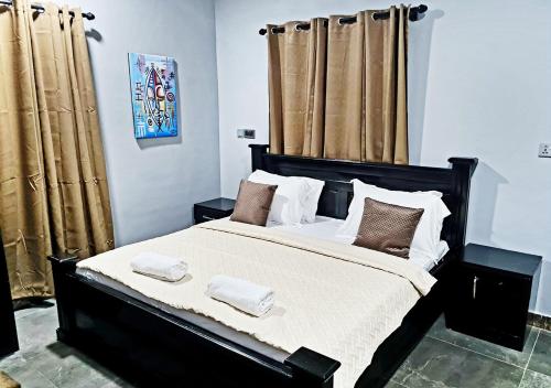 um quarto com uma cama grande e cortinas castanhas em Elegant Escape in Adenta- 2-Bed, 5star Service, Free Wifi, 24-7 Security, Close to Highway, by DLA 