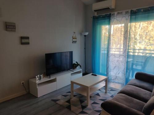 a living room with a couch and a tv and a table at Joli appartement dans quartier calme de Perpignan in Perpignan