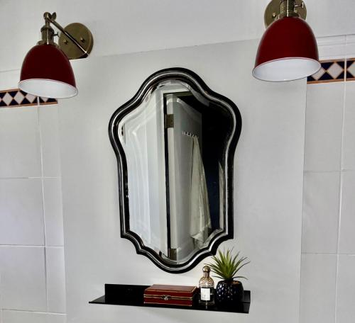 a mirror on a wall with a shelf and two lights at Gîte La Petite Francorchamps Ardennaise in Stavelot
