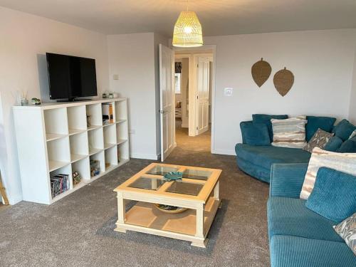 a living room with a blue couch and a coffee table at Contemporary Holiday apartment in Perranporth