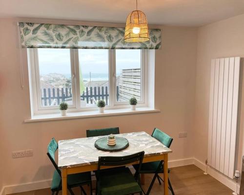 comedor con mesa, sillas y ventana en Contemporary Holiday apartment, en Perranporth