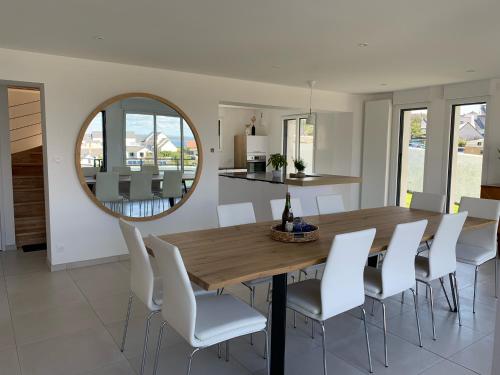 a dining room with a wooden table and white chairs at Maison d'exception ~ Vue Mer ~ 100m de la plage in Camaret-sur-Mer