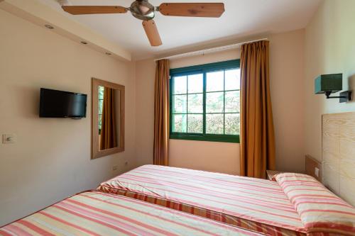 1 dormitorio con 2 camas y ventana en Bungalows Cordial Sandy Golf en Maspalomas
