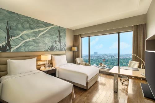 a hotel room with two beds and a desk at The Leela Ambience Convention Hotel Delhi in New Delhi