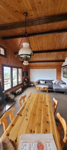 的住宿－Chez Mémé - vue vallée & forêt - linge à disposition，一张大木桌,位于一个配有沙发的房间