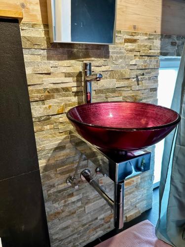 a bathroom with a red sink on a brick wall at La Vie en rose in Greifenberg