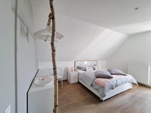 a white bedroom with a bed and a table at Les Arbres sous le vent à 10 min de Pairi Daiza in Jurbise