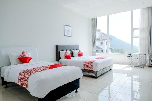 a bedroom with two beds and a large window at OYO 1194 Villa Bukit Panderman Residence in Tlekung