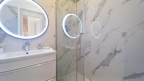 ein Badezimmer mit Dusche, Waschbecken und Spiegel in der Unterkunft Trident A in Cannes