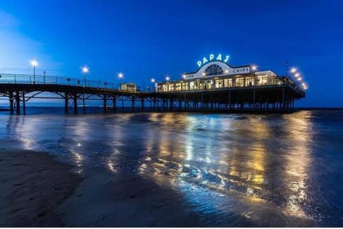 a pier with a building on the beach at night at Jalebo in Cleethorpes