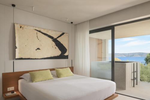 Steni Vala AlonissosにあるIlya Botanic Suitesのベッドルーム(白いベッド1台、大きな窓付)