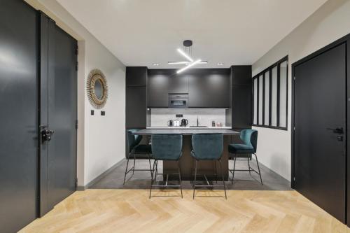 una cocina con armarios negros, mesa y sillas en 327 Suite Le Marais - Superb apartment in Paris, en París