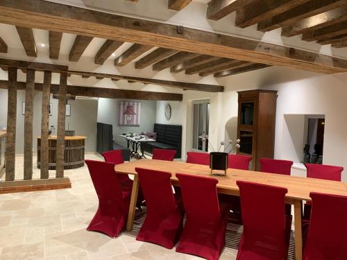 Cette grande chambre comprend une table en bois et des chaises rouges. dans l'établissement Le Verger Des Pierres Blanches, à Mont-près-Chambord