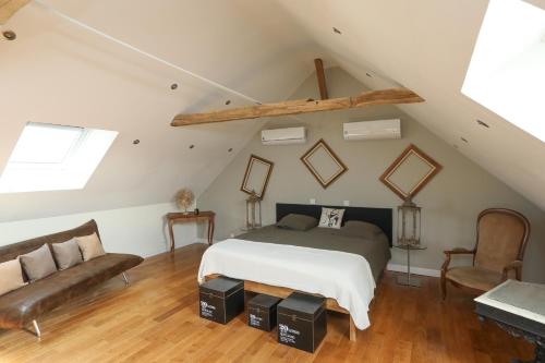 - une chambre mansardée avec un lit et un canapé dans l'établissement Le Verger Des Pierres Blanches, à Mont-près-Chambord