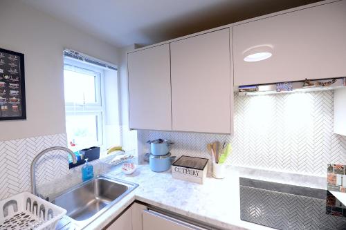 uma cozinha com armários brancos e um lavatório em 2 BEDROOM FLAT in WOOD GREEN PICCADILLY LINE em Londres