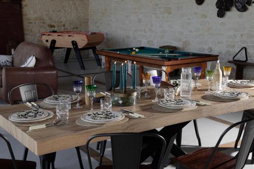 a wooden table with plates and glasses and a pool table at L'Intemporelle in Landrais