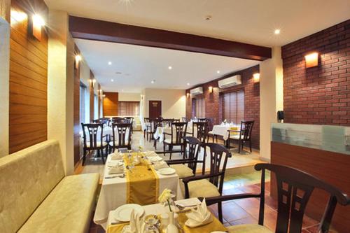 uma sala de jantar com mesas e cadeiras num restaurante em JK Park Residency em Cananor
