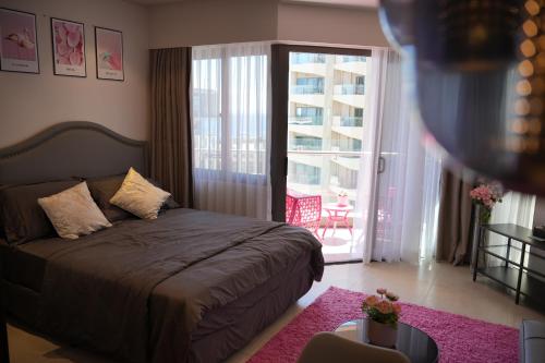 Dominiks Modern pink Studio Balcony & Ocean View Balcony 11 Floor Fast-Wifi at Tambuli Resort في Maribago: غرفة نوم بسرير وشرفة
