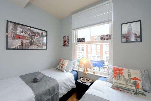 1 dormitorio con 2 camas y ventana en 2 BEDROOM FLAT in WOOD GREEN PICCADILLY LINE, en Londres
