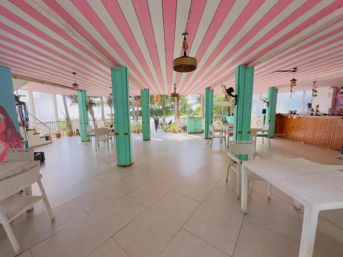 Habitación con techo rosa y verde, mesas y sillas. en Melba Beach Resort By Maitree en Arambol