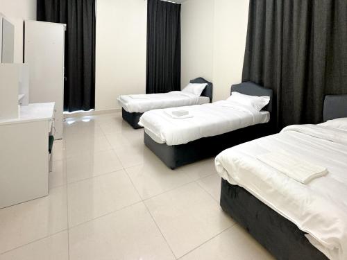 two beds in a room with black curtains at Lehbab Star Residence - Home Stay in Dubai