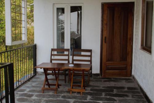 a wooden table and two chairs on a porch at The Lodge at Wah, Kandbari in Pālampur