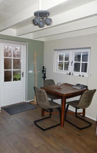a dining room with a wooden table and chairs at The Green Cottage in Ruinen