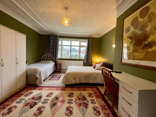 a bedroom with two beds and a desk and a window at Saint Gabriel's Road Guesthouse in London