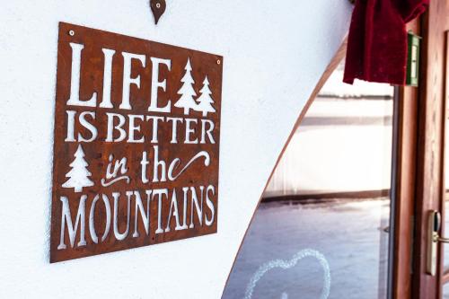 um sinal na parede que lê a vida é melhor nas montanhas em Arlen Lodge Hotel em Sankt Anton am Arlberg