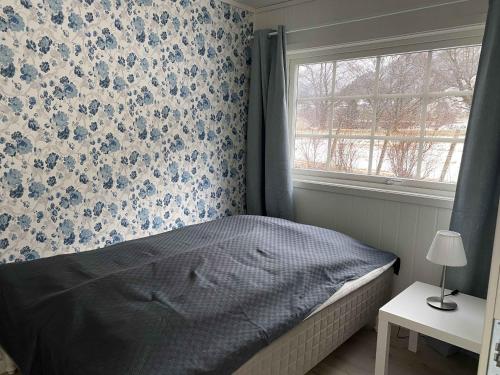 1 dormitorio con 1 cama y una ventana con flores azules en Rosendal Apartments Motellet en Rosendal