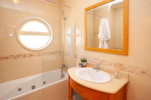 ein Badezimmer mit Waschbecken, Spiegel und Badewanne in der Unterkunft Encosta da Orada by OCvillas in Albufeira