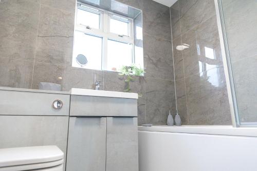 a bathroom with a tub and a toilet and a window at Jalebo in Cleethorpes