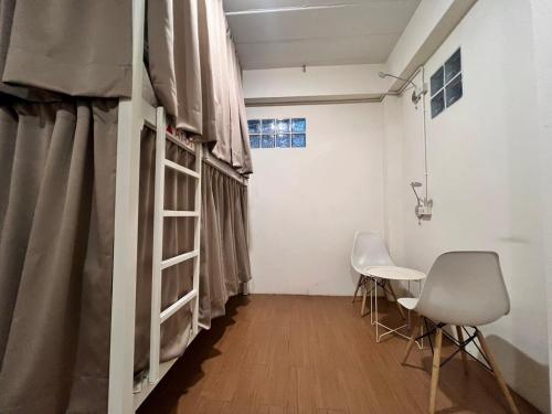 a room with a bed and two chairs and a table at Allred Hostel Chiangmai in Chiang Mai