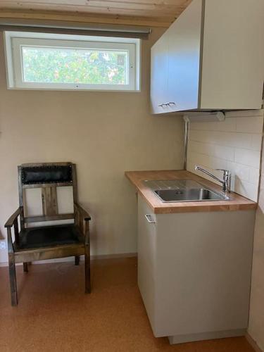 a kitchen with a sink and a chair and a window at Garden house near centre in Tampere