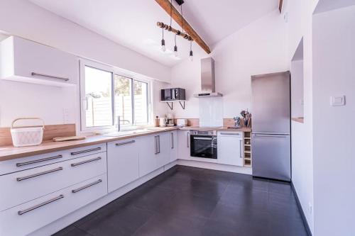 une grande cuisine blanche avec des armoires et des appareils blancs dans l'établissement La Butte : Bol d'air iodé assuré, à Urville-Nacqueville