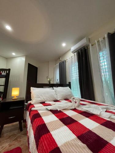 a bedroom with a bed with a red and white blanket at Point Vista Transient Accomodation in Daet