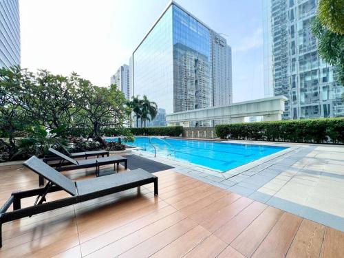 a swimming pool with two benches and a building at Two Bedroom Condo in BGC with Balcony, Sauna, & Pool in Manila
