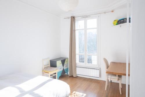 um quarto com uma cama, uma secretária e uma janela em Cosy and very nice flat with open view on a parc em Paris