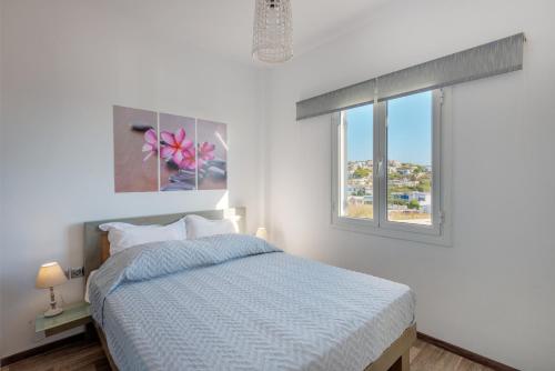 a white bedroom with a bed and a window at Aegean Paradiso Vacation Club - "Adults Only" in Azolimnos