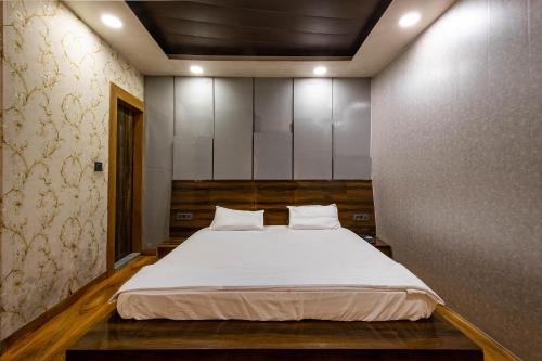 een slaapkamer met een groot bed met witte lakens bij FabHotel Le Masrana Inn in Mussoorie