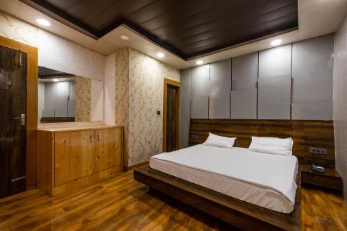 een slaapkamer met een groot wit bed en een spiegel bij FabHotel Le Masrana Inn in Mussoorie