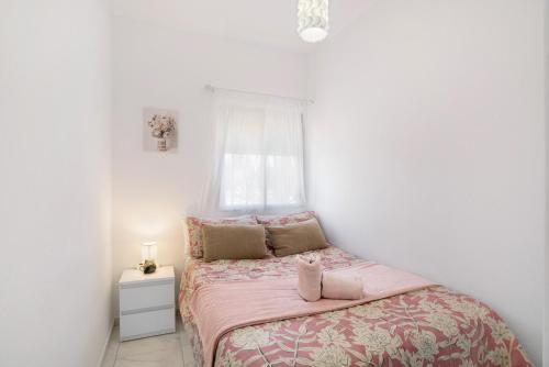 a bedroom with a bed with pink sheets and a window at Un descanso 2-1 in Maspalomas