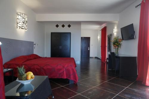 1 dormitorio con cama roja y sala de estar en La Poste, en Antsiranana